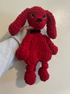 red crochet dog in front of plain wall