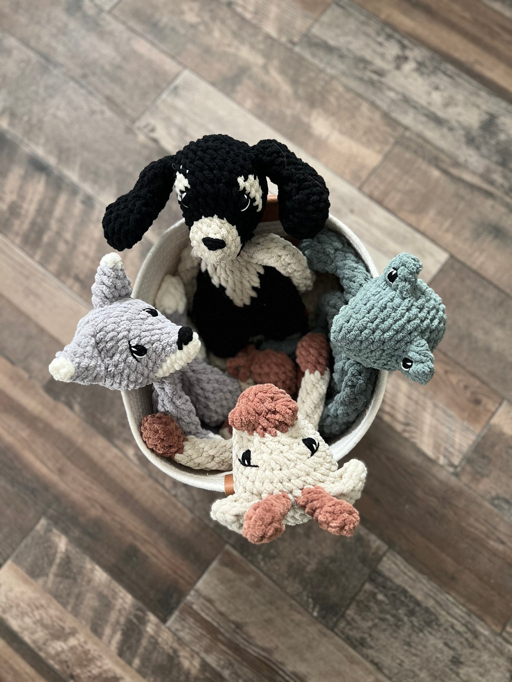 Four crochet animals in a basket on the floor