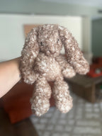 Crocheted bunny held by a hand with a blurred background