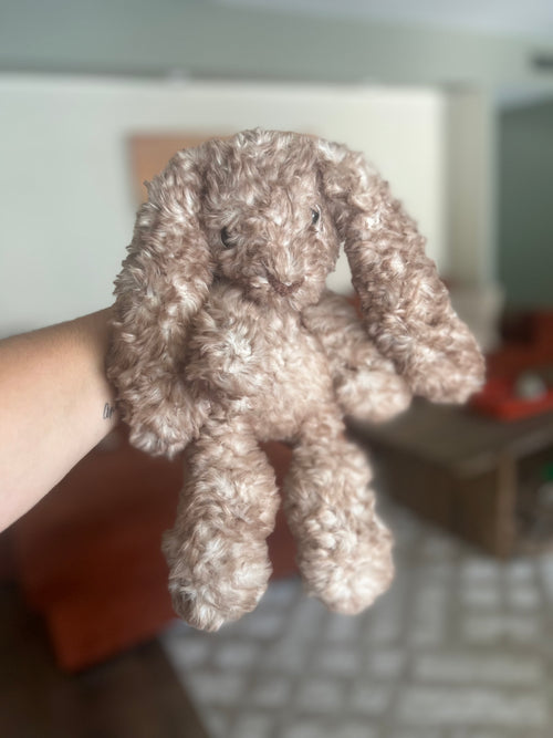 Crocheted bunny held by a hand with a blurred background