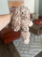 Crocheted bunny held by a hand with a blurred background