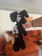 black and grey crochet dog in front of blurred orange couch