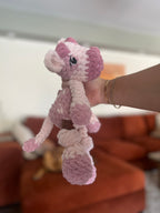 pink crochet cow in front of blurred orange couch