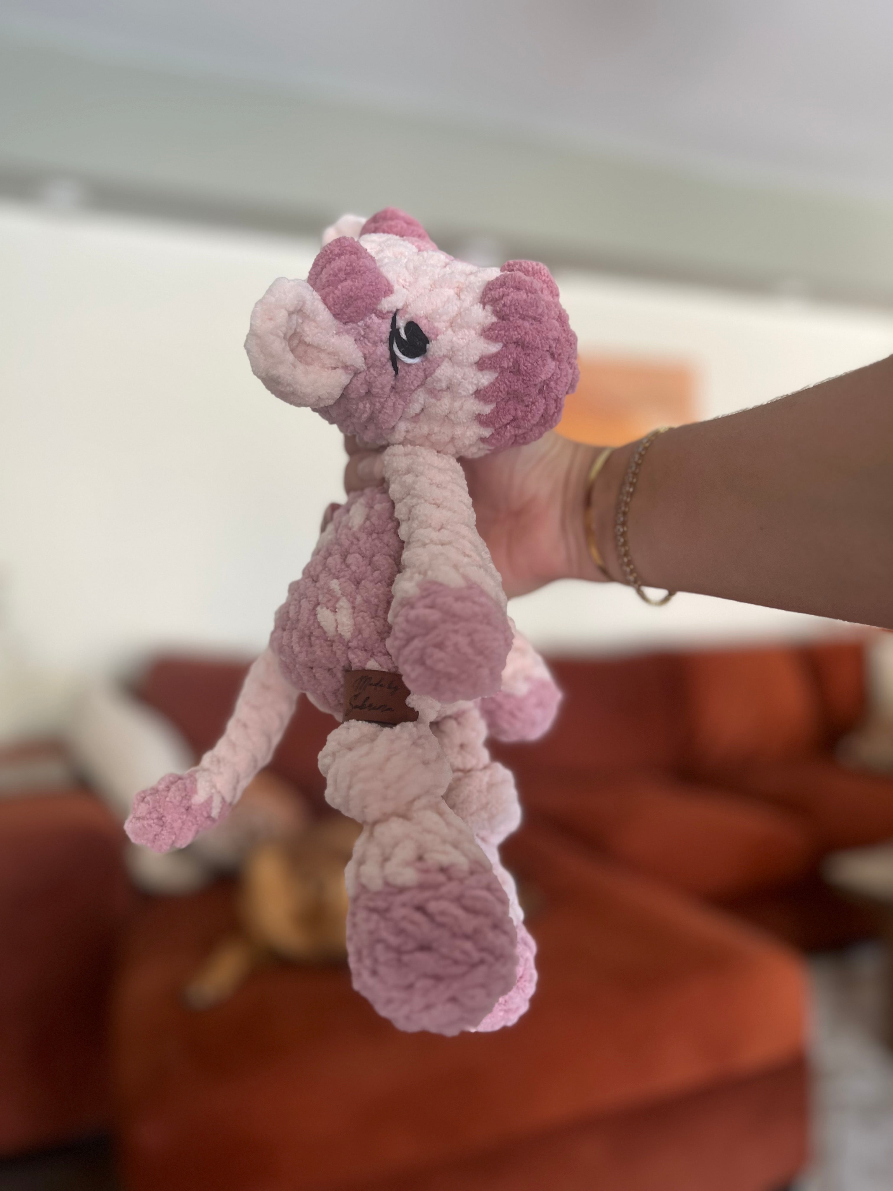 pink crochet cow in front of blurred orange couch