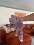 purple crochet hippo in front of blurred orange couch