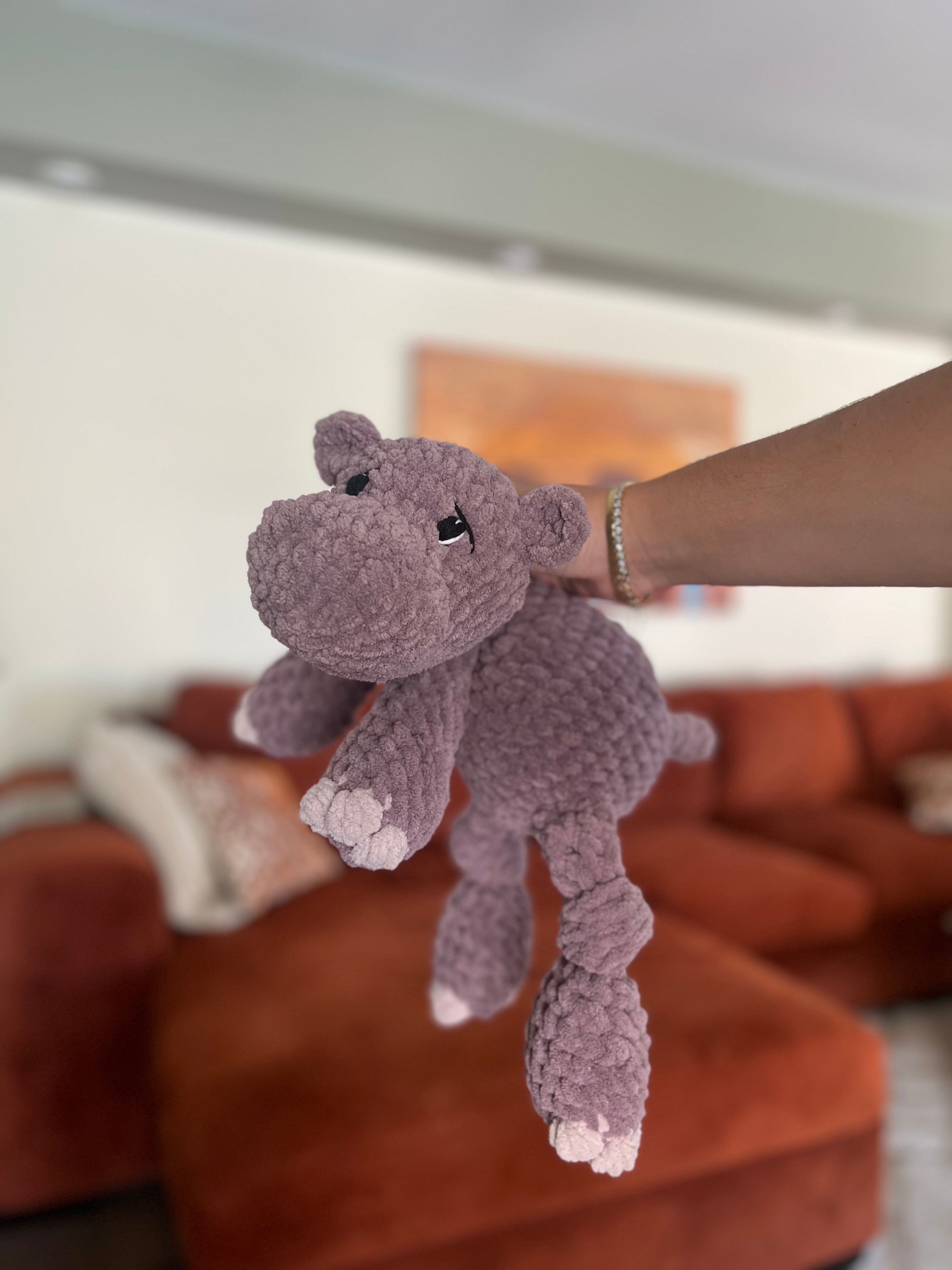 purple crochet hippo in front of blurred orange couch