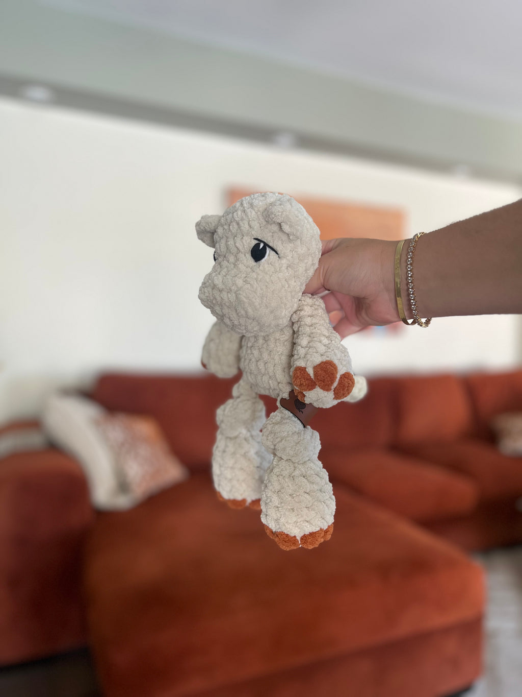 white crochet hippo with orange toes in front of blurred orange couch