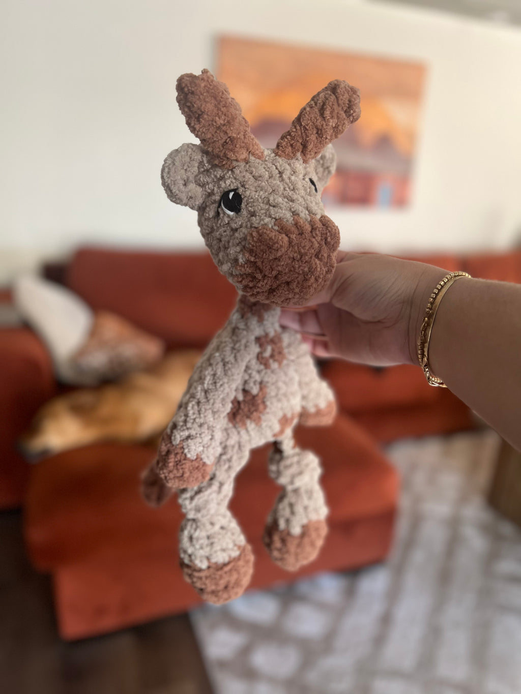 Hand holding small crochet giraffe plushie with blurred background
