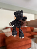 heather black hippo crochet plushie in front of orange blurred couch