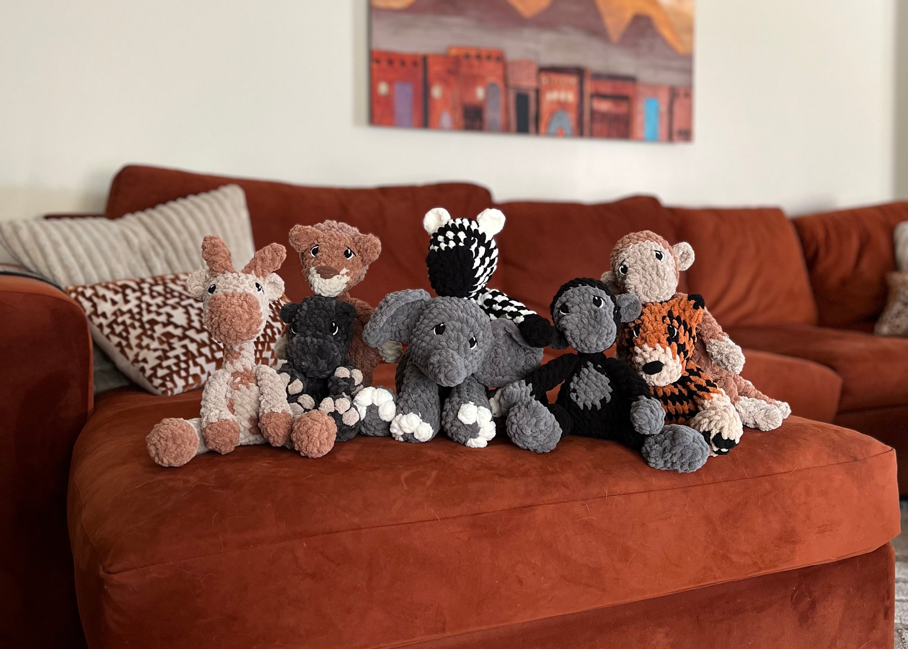 Plush toys on a brown sofa with a painting in the background