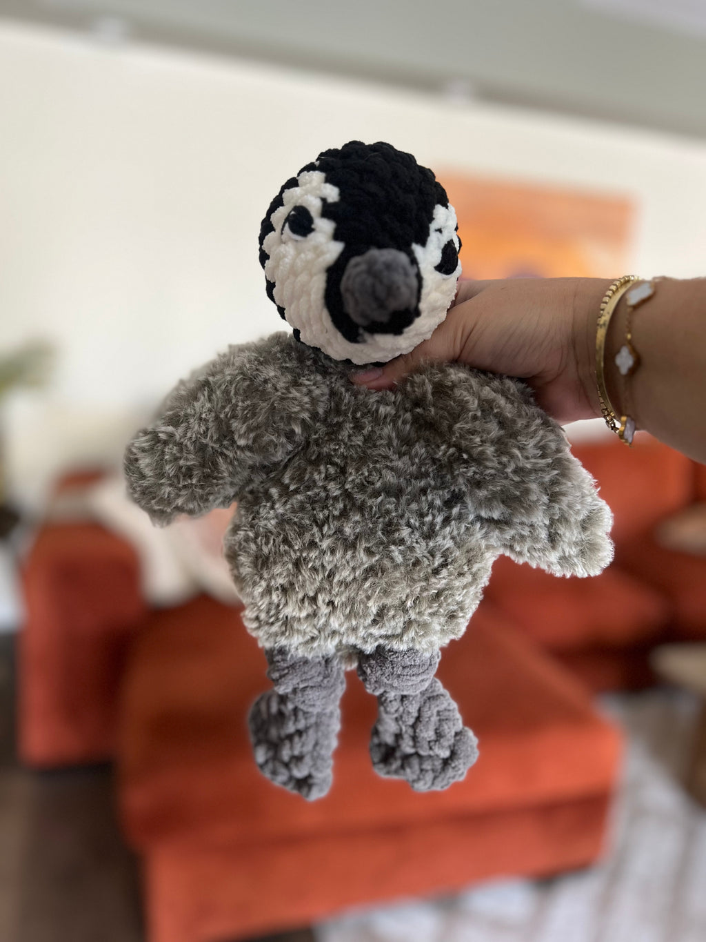 Hand holding a small crochet penguin made partially with faux fur yarn