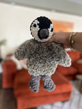 Hand holding a small crochet penguin made partially with faux fur yarn