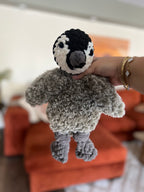 Hand holding a small crochet penguin made partially with faux fur yarn
