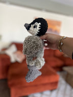 Hand holding a small crochet penguin made partially with faux fur yarn
