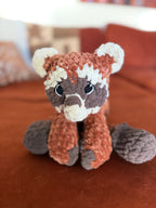 Red panda plushie on orange couch