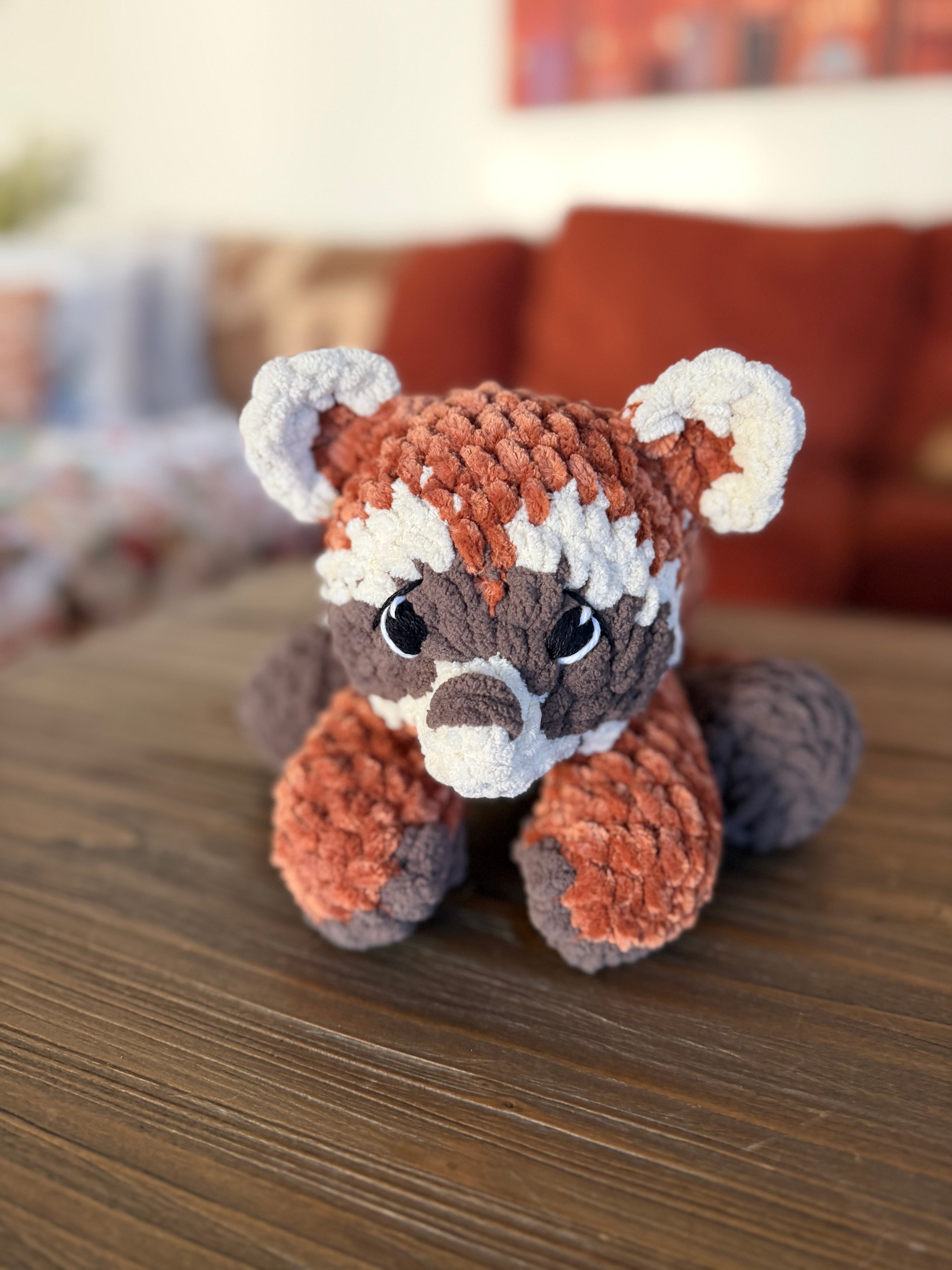 Red panda plushie on a wooden surface with a blurred background