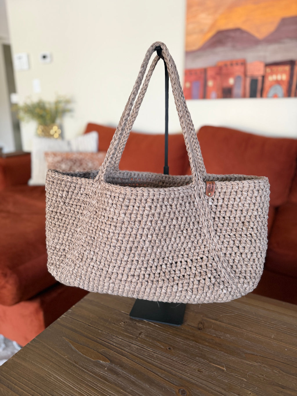 Beige crochet tote bag on a handle in a living room setting