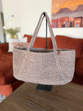 Beige crochet tote bag on a handle in a living room setting