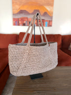 Beige crochet tote bag on a handle in a living room setting