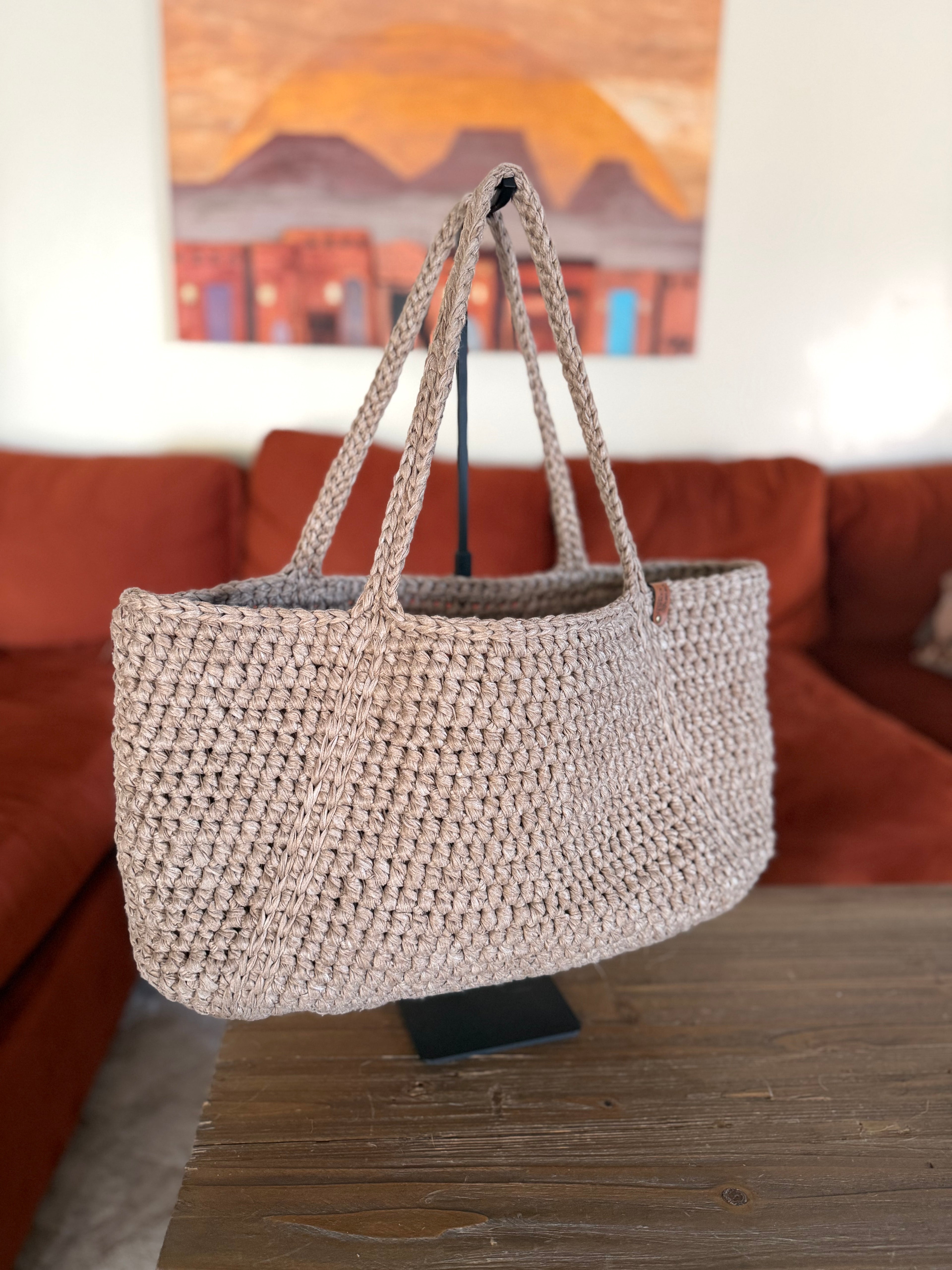 Beige crochet tote bag on a handle in a living room setting