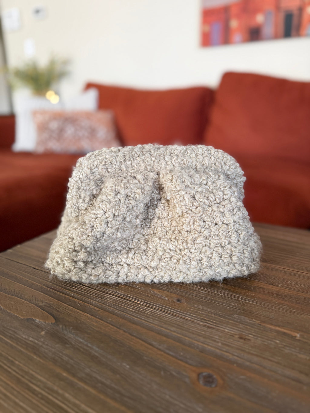 Beige crochet clutch in front of blurred orange couch