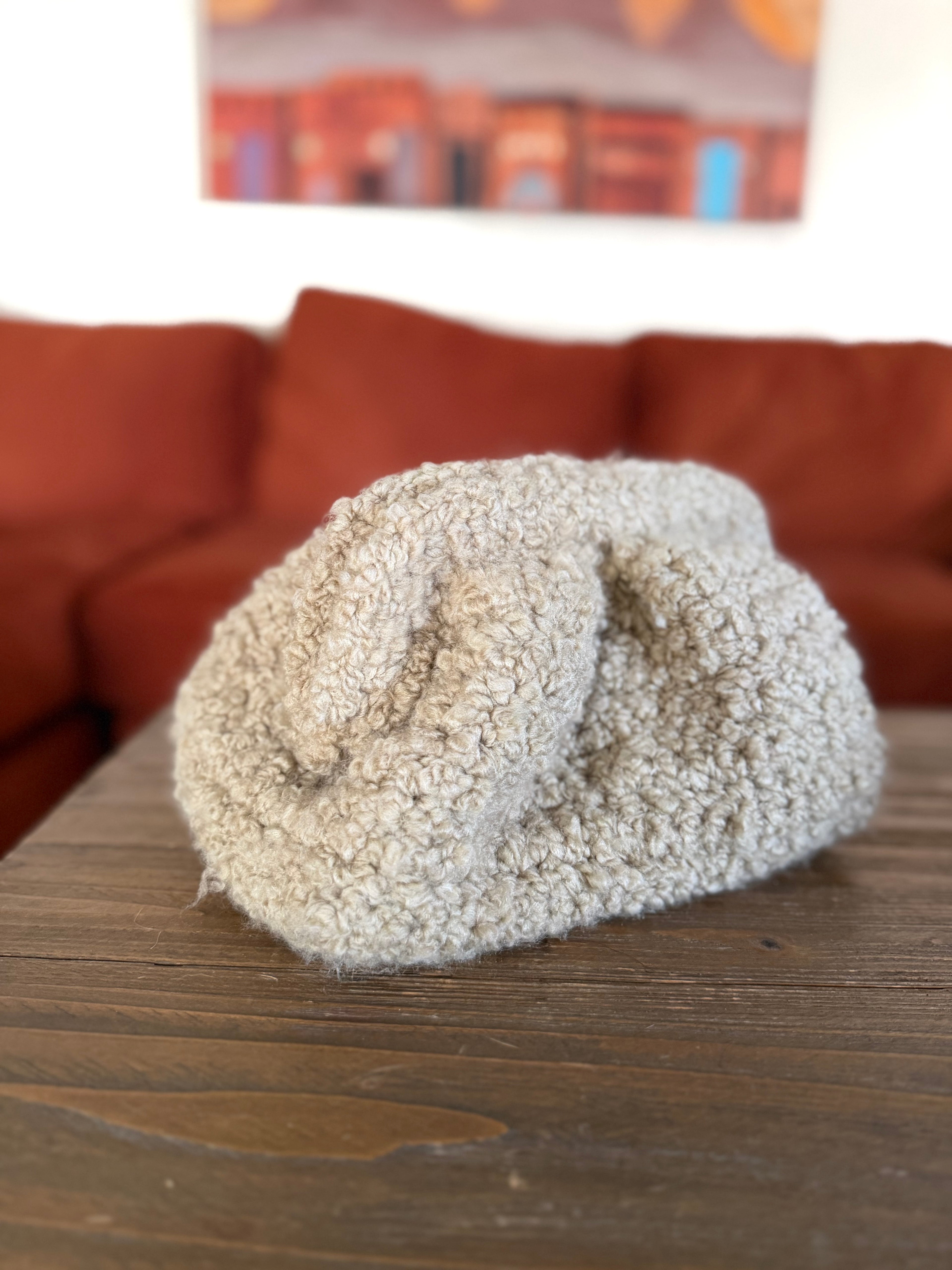 Beige crochet clutch in front of blurred orange couch
