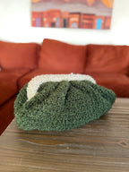 Green crochet clutch on a wooden table with a brown sofa and colorful painting in the background