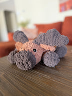 dark and light brown crochet moose in front of blurred orange couch