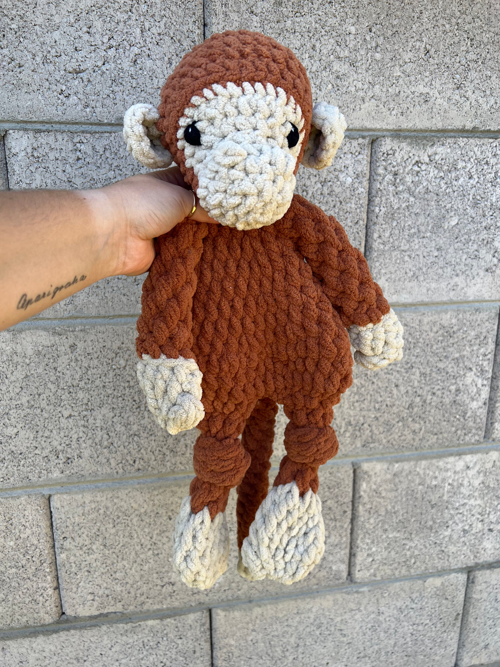 brown and tan monkey in front of grey brick wall