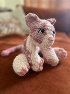 Mutli-colored pink crochet cat on an orange couch