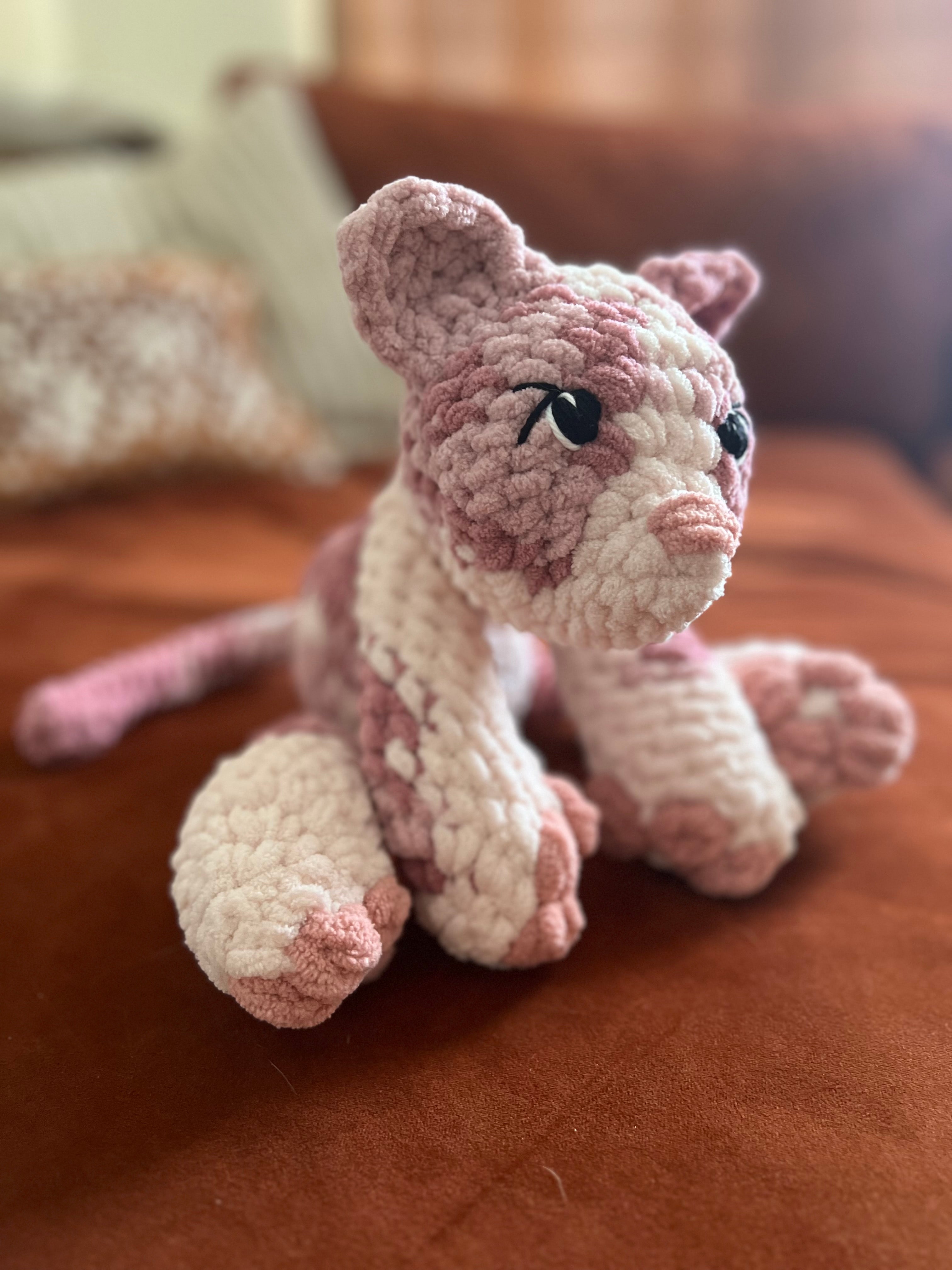 Mutli-colored pink crochet cat on an orange couch