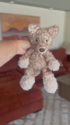 Crocheted light tan fox held by a hand with a blurred background rotating around