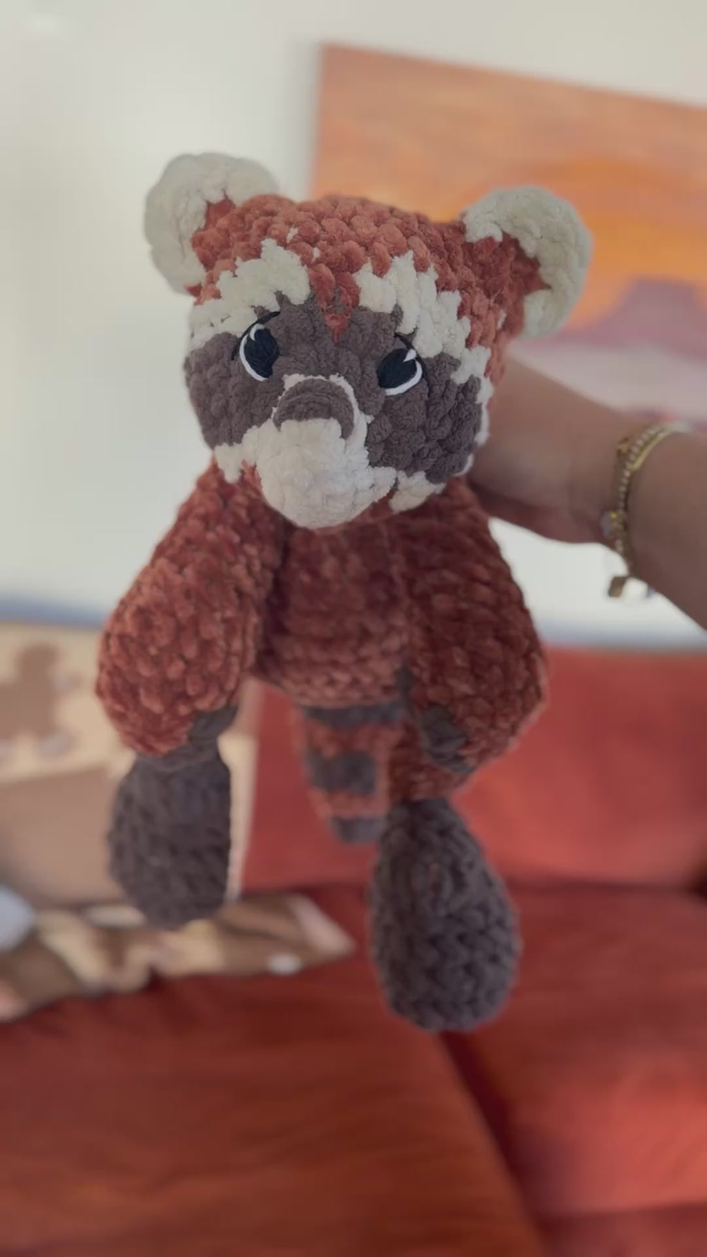 video of red panda plushie being rotated in front of orange couch